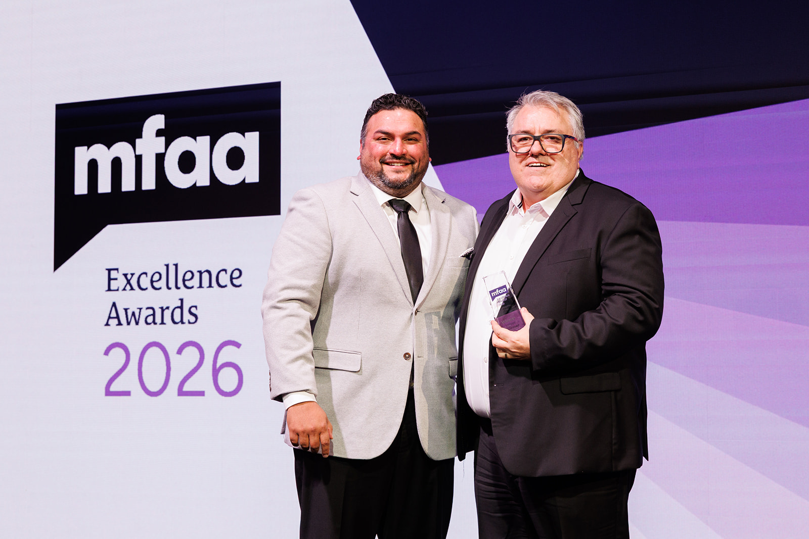 Andrew Larcombe receiving an MFAA Excellence Award on stage in 2026